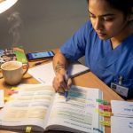 Indian nurse studying B1 German grammar with highlighted textbook pages on a desk