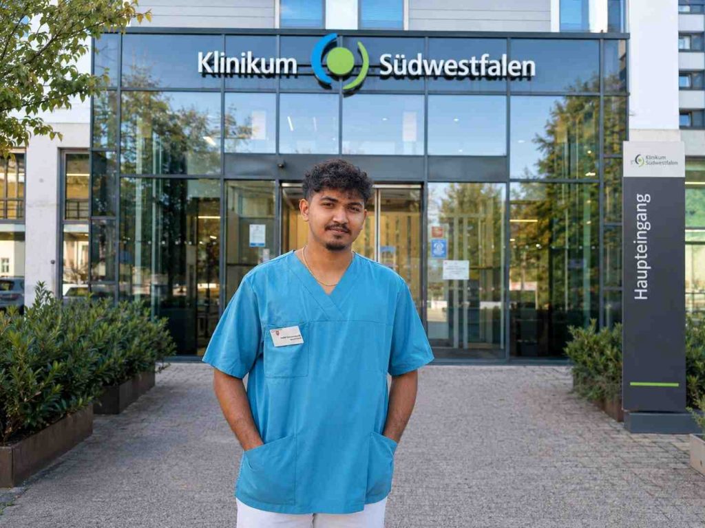Muhammad Sami Nizar in his work uniform outside a University Clinic in Germany, smiling confidently