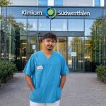Muhammad Sami Nizar in his work uniform outside a University Clinic in Germany, smiling confidently